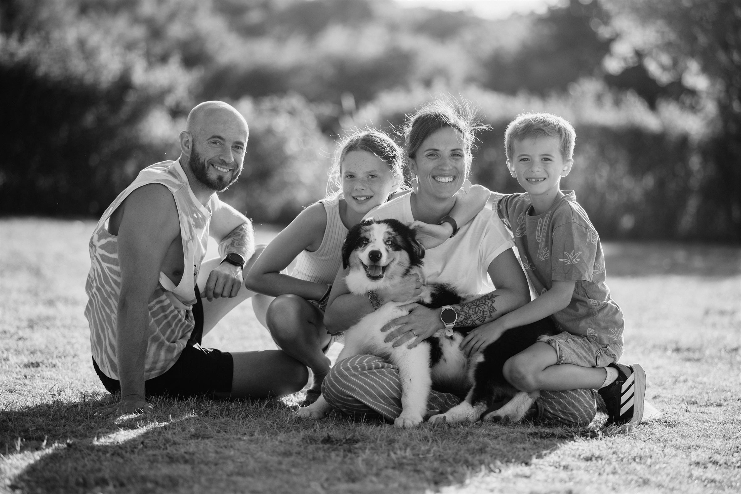 Famille et leur chien assis dans l'herbe, noir et blanc