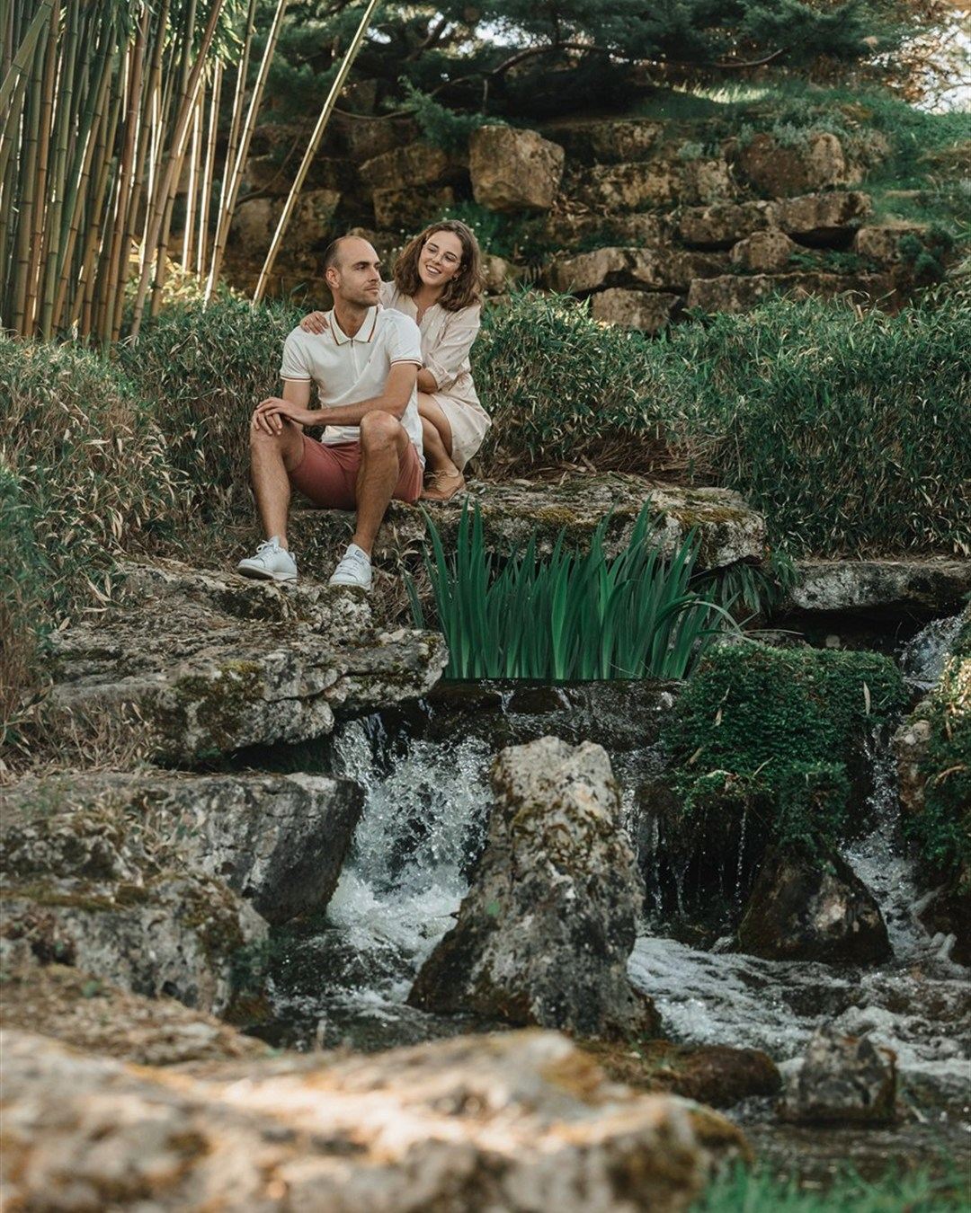 Couple assis sur les rochers au-dessus d'une petite cascade