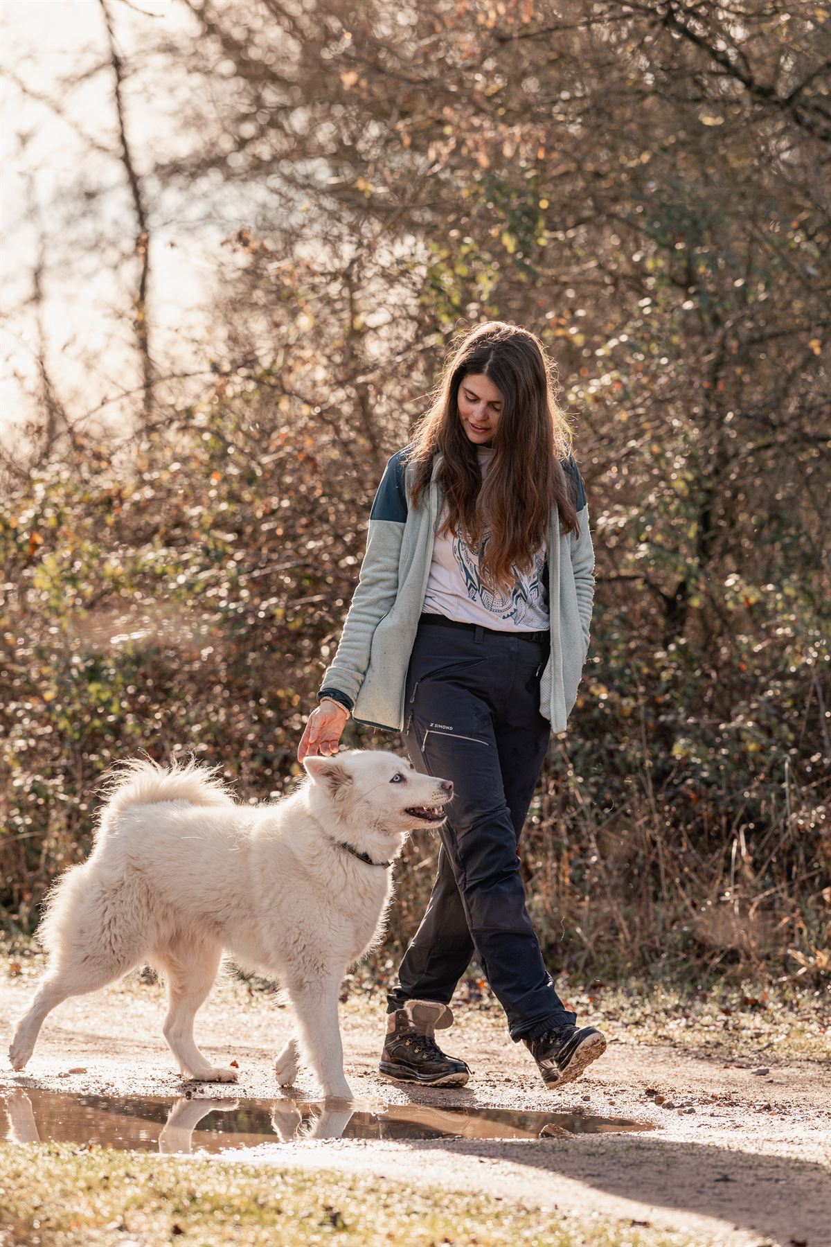 Jeune femme promenant un chien blanc sur un chemin
