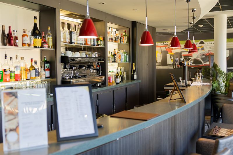 Bar d'hôtel aux suspensions rouges et comptoir arrondi