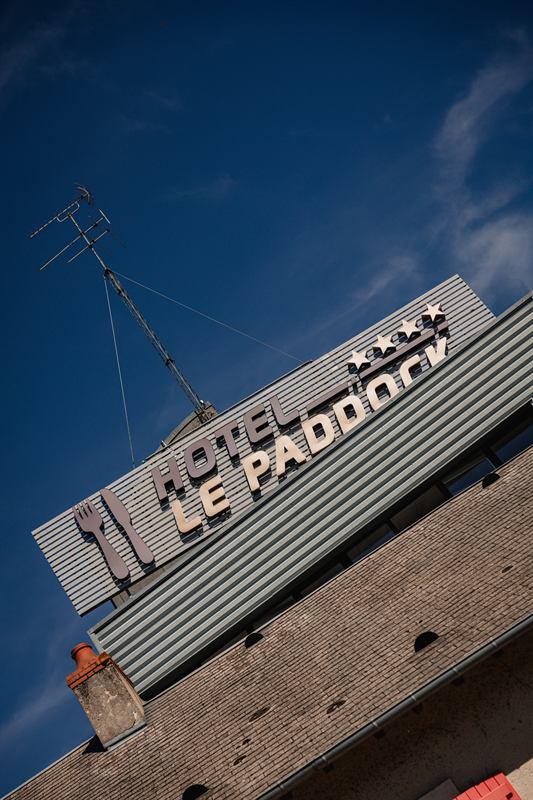 Enseigne de l'hôtel Le Paddock sur fond de ciel bleu