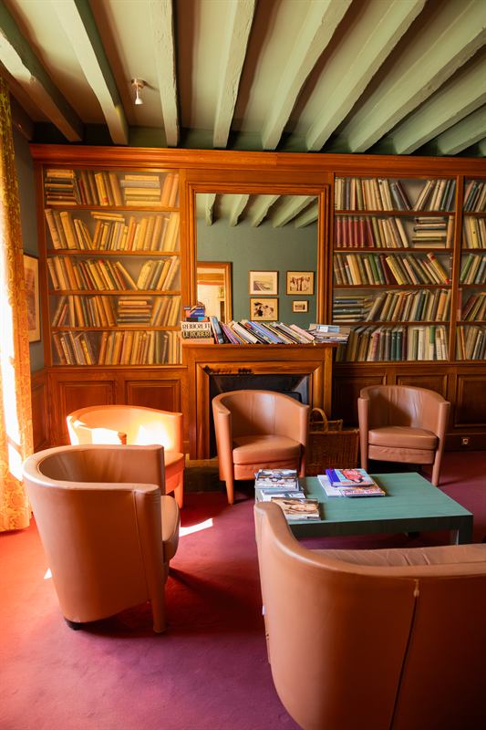 Salon bibliothèque d'hôtel aux fauteuils club en cuir