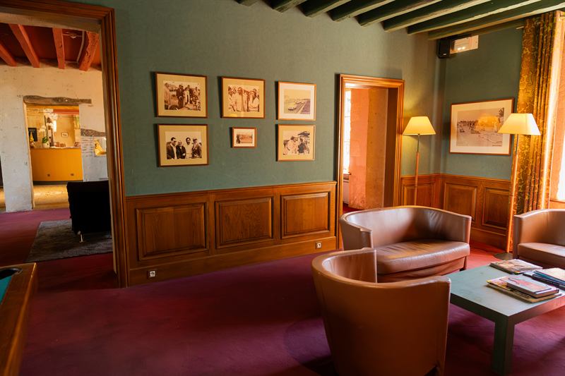 Salon d'hôtel aux murs verts, fauteuils et cadres anciens