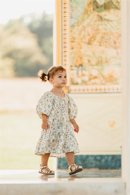 Petite fille en robe fleurie devant un pavillon peint