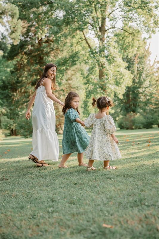Maman et ses filles dansant en ronde dans l'herbe