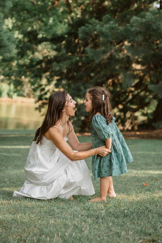Maman agenouillée face à sa fille, au bord d'un étang