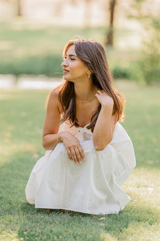 Portrait d'une maman accroupie dans l'herbe, robe blanche