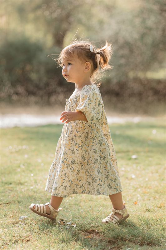 Petite fille en robe fleurie marchant dans la lumière du soir
