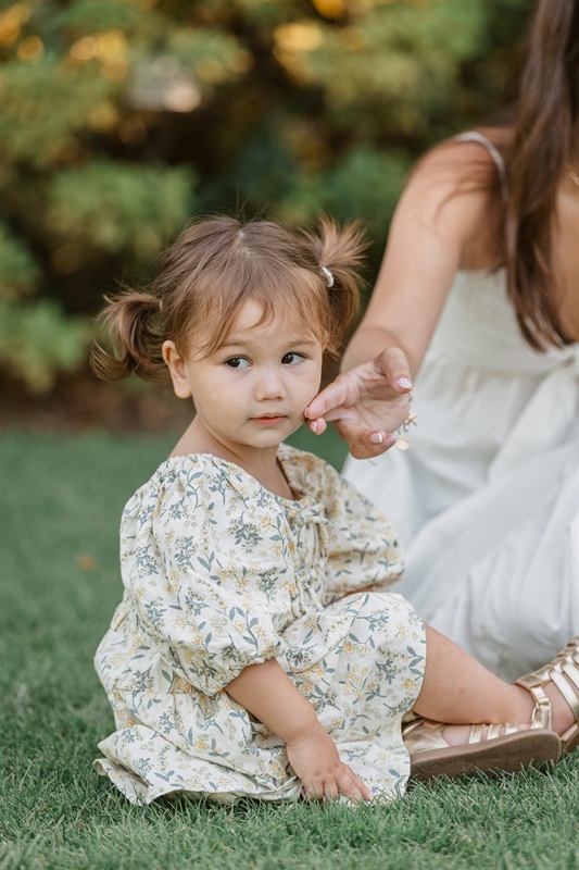Bébé assise dans l'herbe, la main de sa maman tendue vers elle