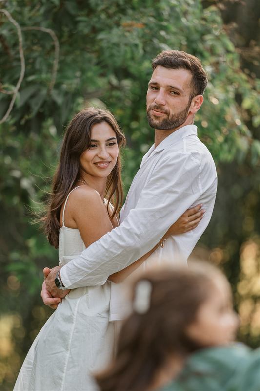 Couple enlacé souriant, leur fille floue au premier plan