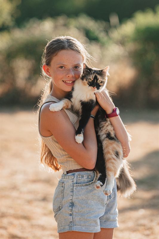 Jeune fille serrant son chat contre elle, lumière dorée
