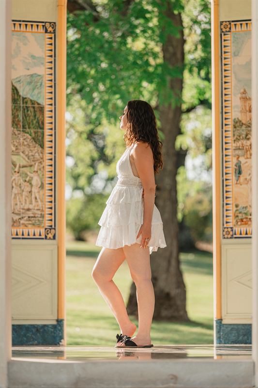 Jeune femme en robe blanche entre les colonnes d'un pavillon peint