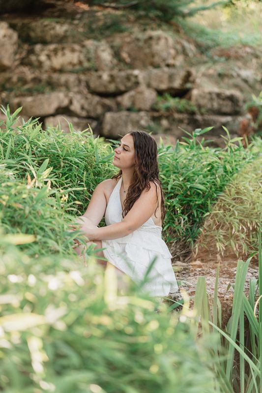 Jeune femme assise dans les herbes hautes au pied d'un rocher