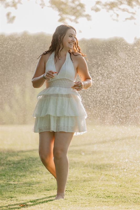 Jeune femme dansant dans une pluie de gouttelettes au soleil
