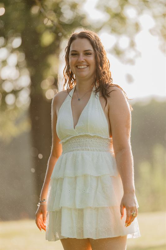 Jeune femme souriante en robe blanche, contre-jour du soir