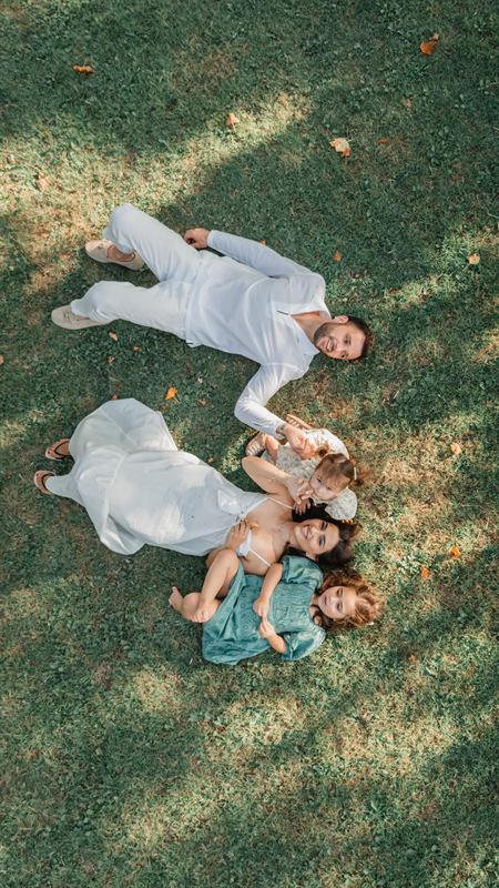 Famille allongée en étoile dans l'herbe, vue du dessus